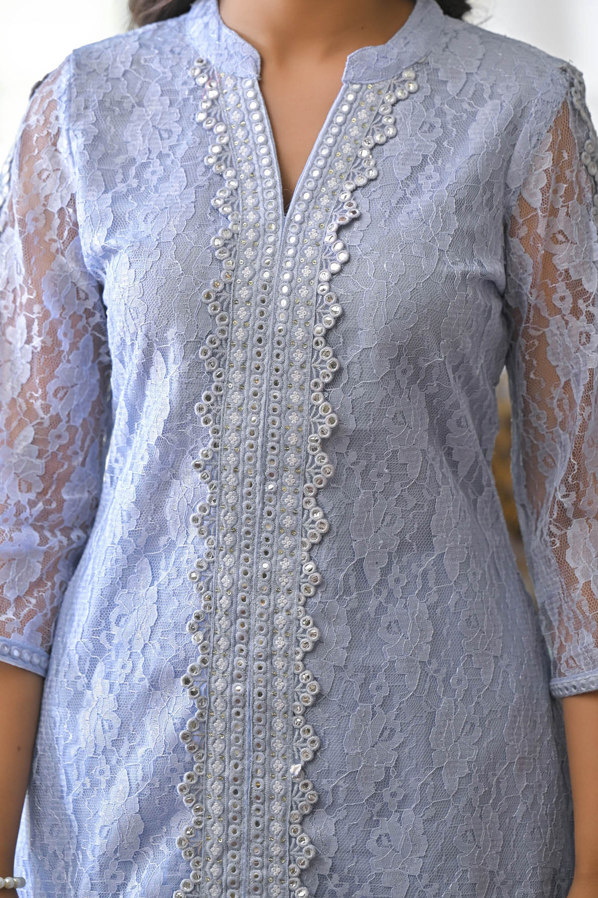 Light blue lace dress with intricate detailing on a plain background