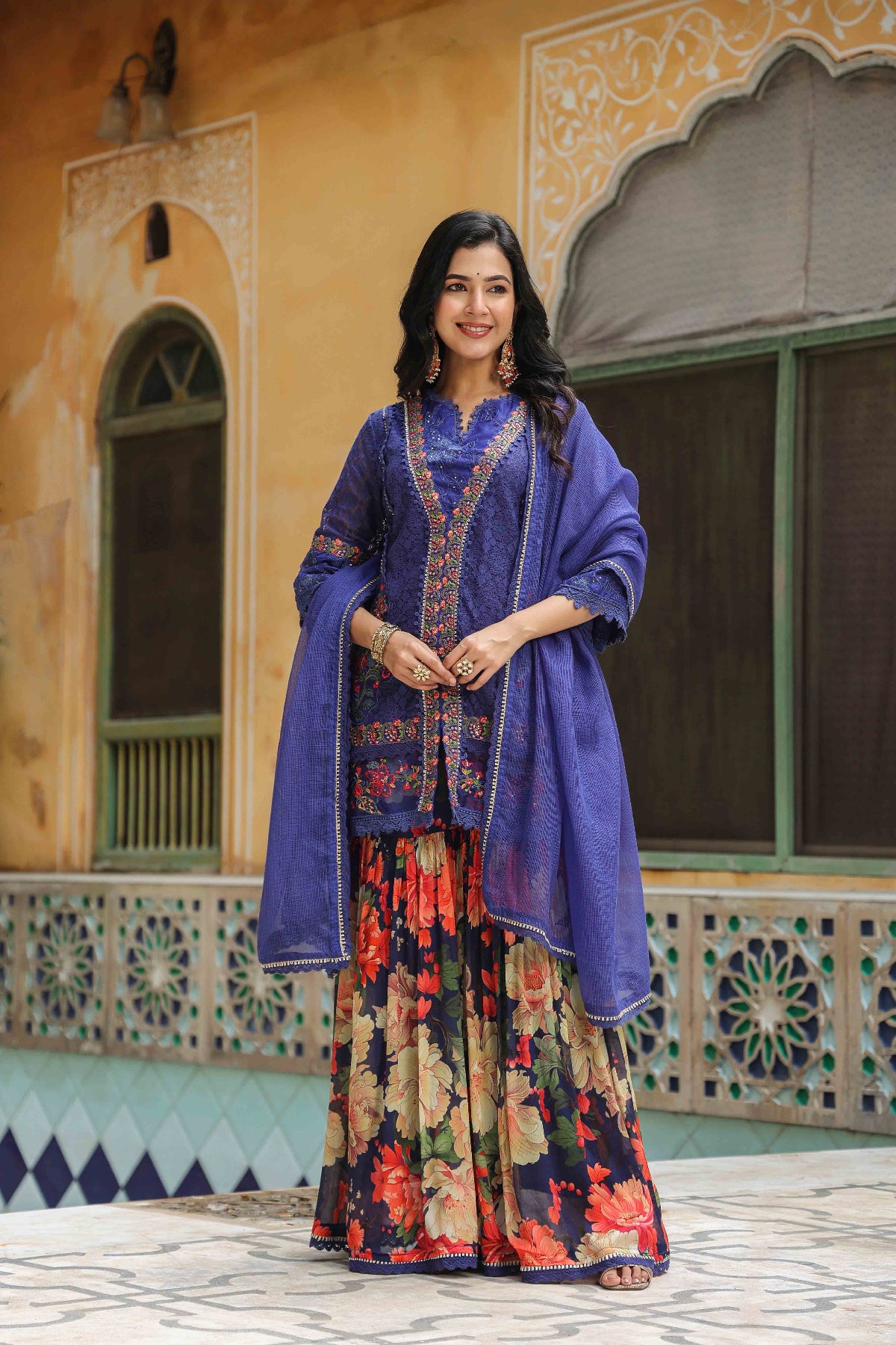 Woman in traditional attire standing in front of a decorative building.