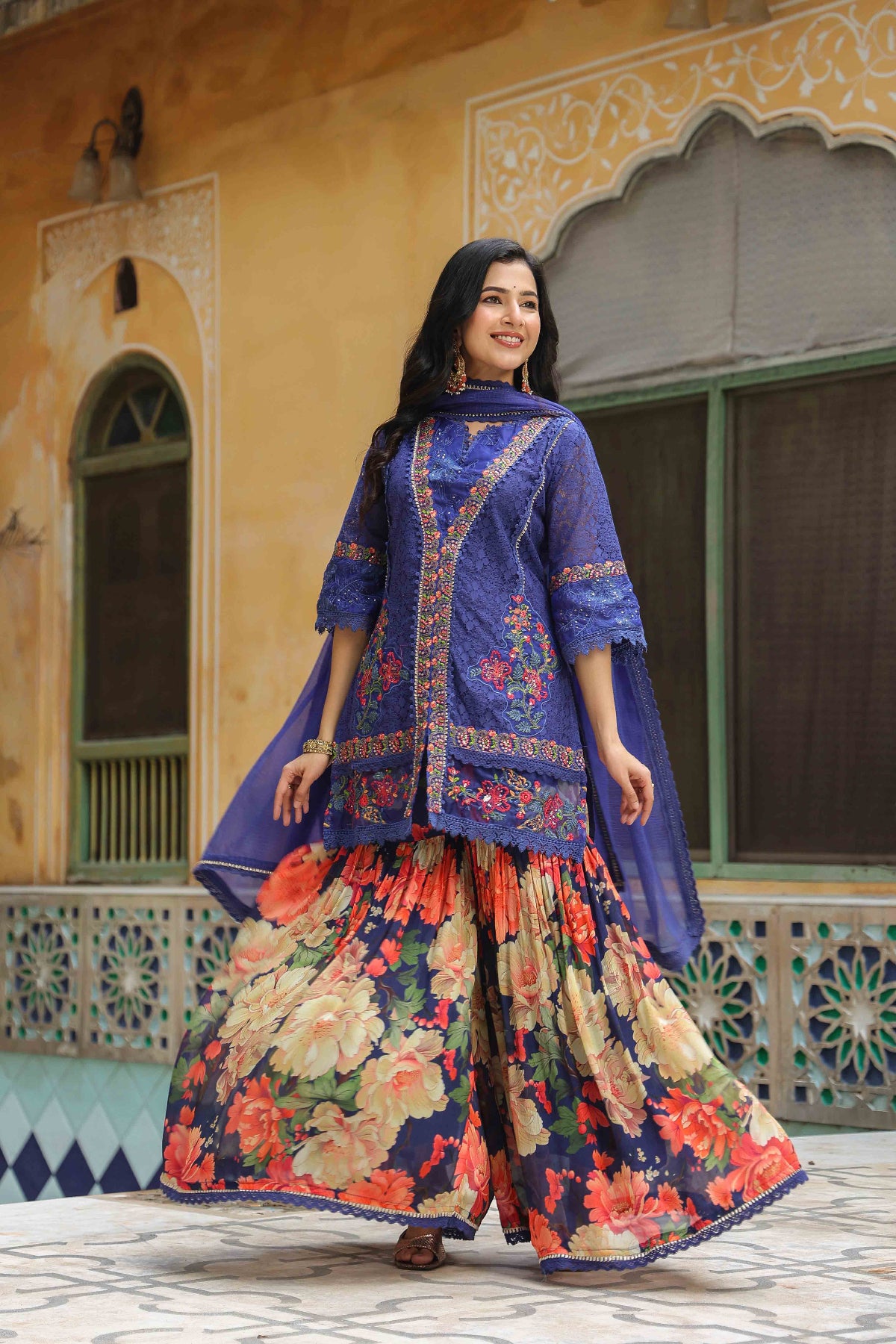 Woman in a traditional outfit standing in front of a decorative building.