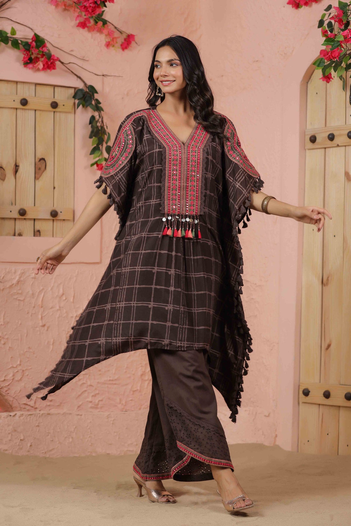Woman wearing a traditional outfit with a checkered design in front of a pink wall.