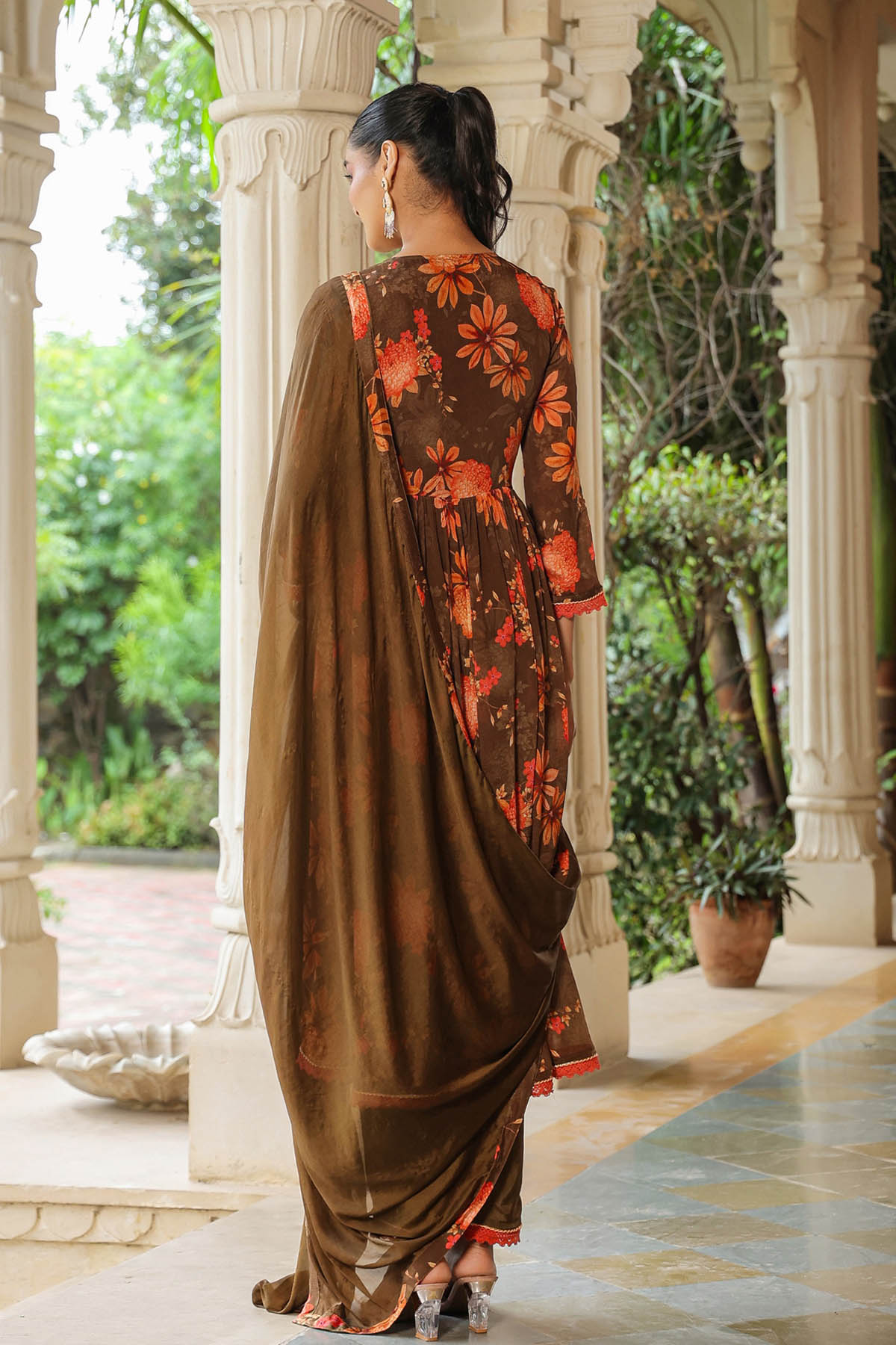 Woman in a traditional outfit with floral patterns standing in an outdoor setting.