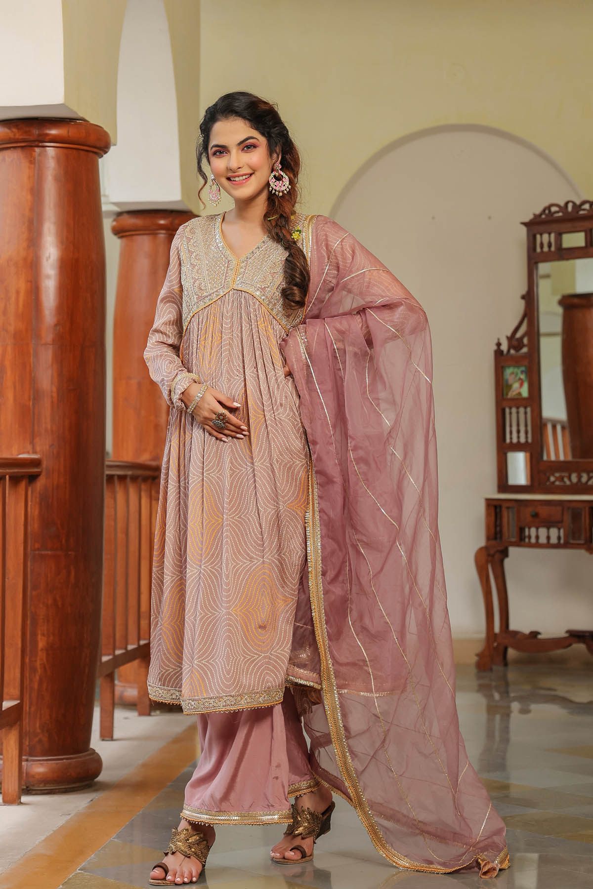 Woman in a traditional pink and beige outfit standing in an indoor setting.