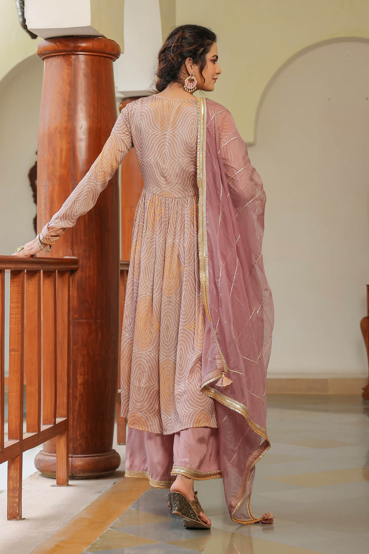 Woman in a traditional outfit standing in a room with wooden columns.