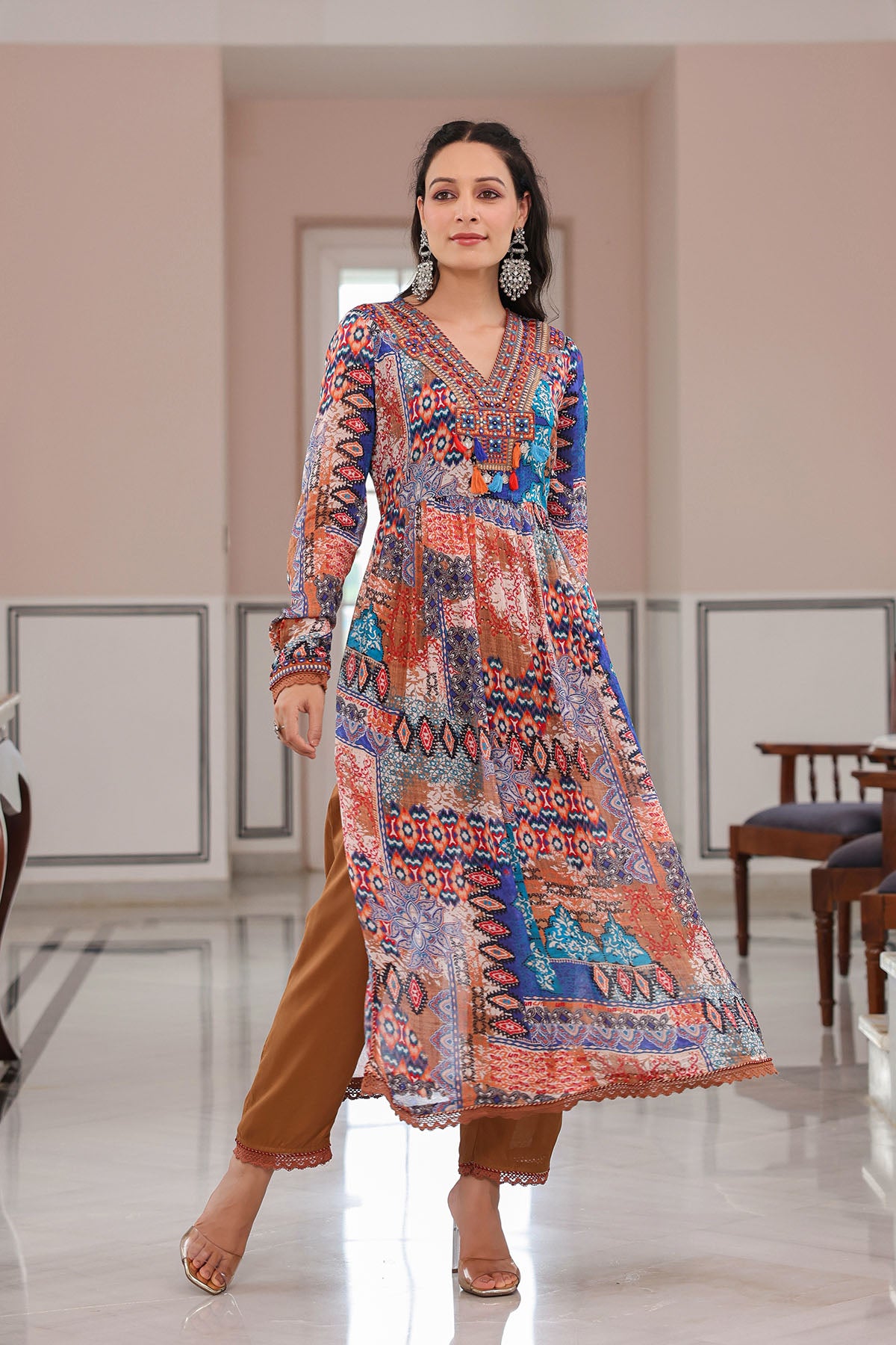 Woman wearing a colorful patterned dress in a room with wooden furniture.