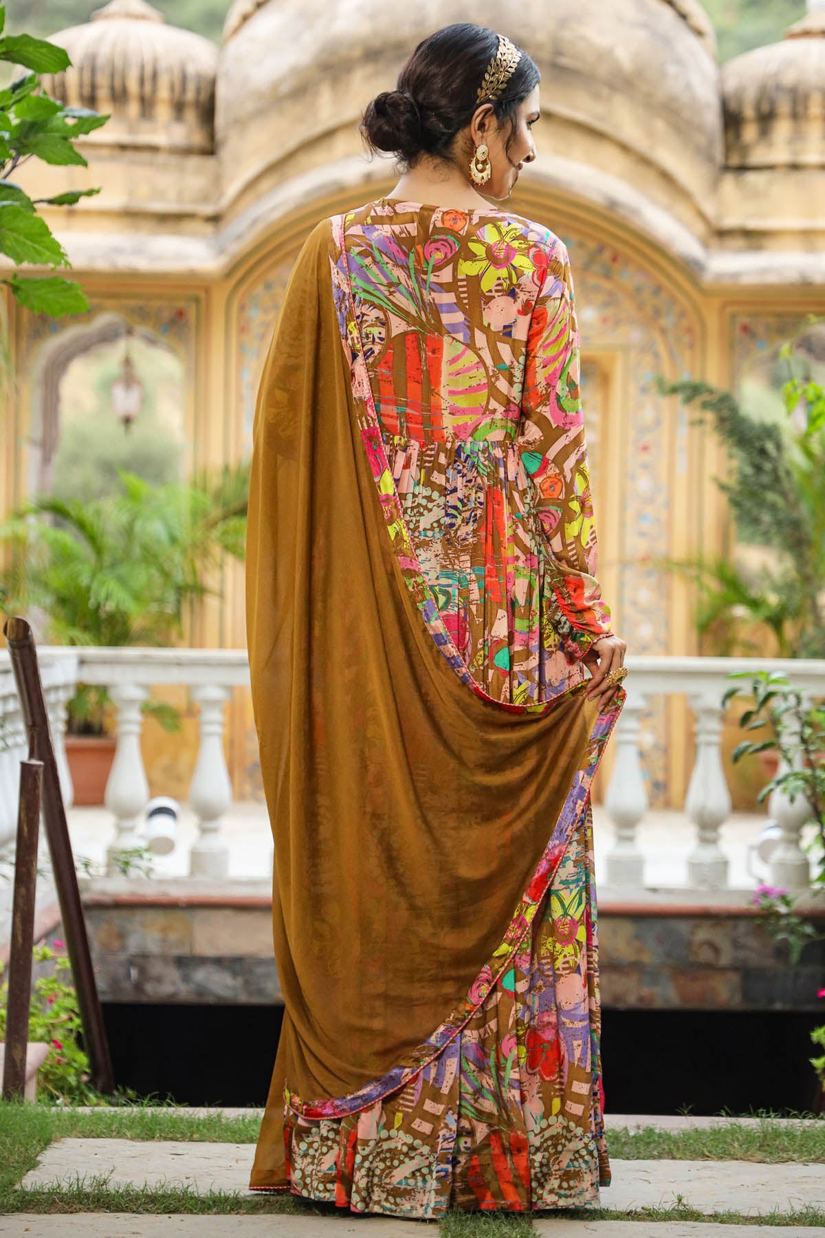 Woman wearing a colorful saree with a traditional architectural background