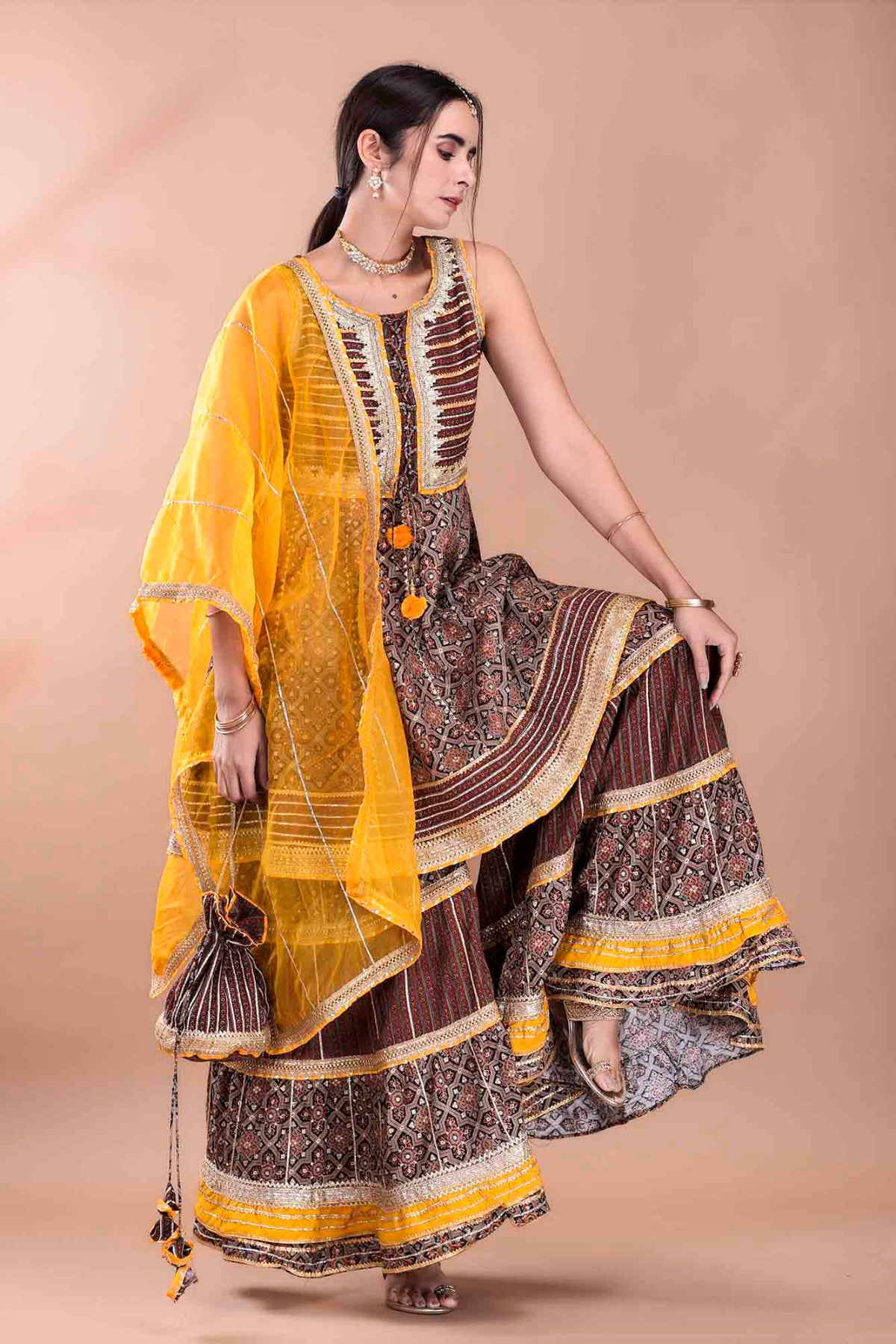 Woman wearing a traditional outfit with a yellow dupatta on a beige background