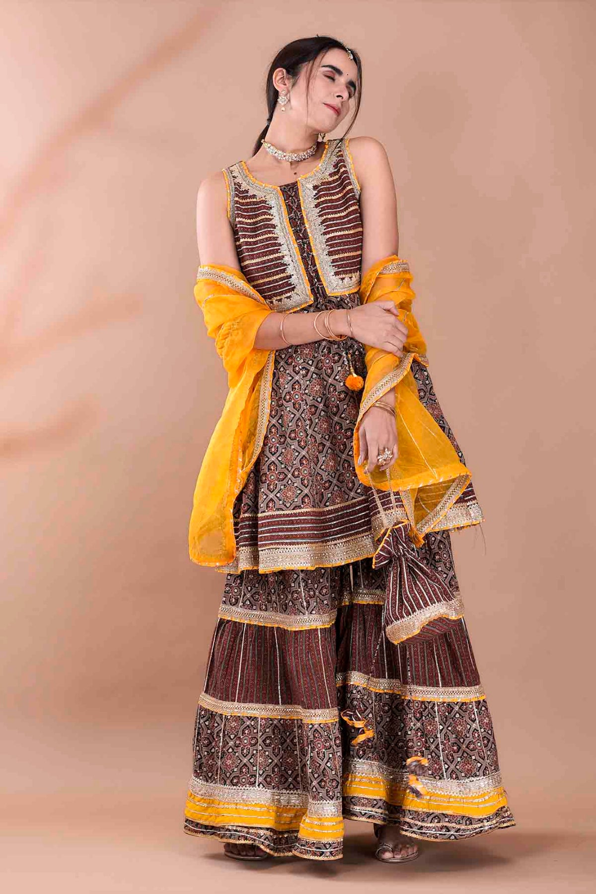 Woman wearing a traditional outfit with yellow and brown patterns on a beige background
