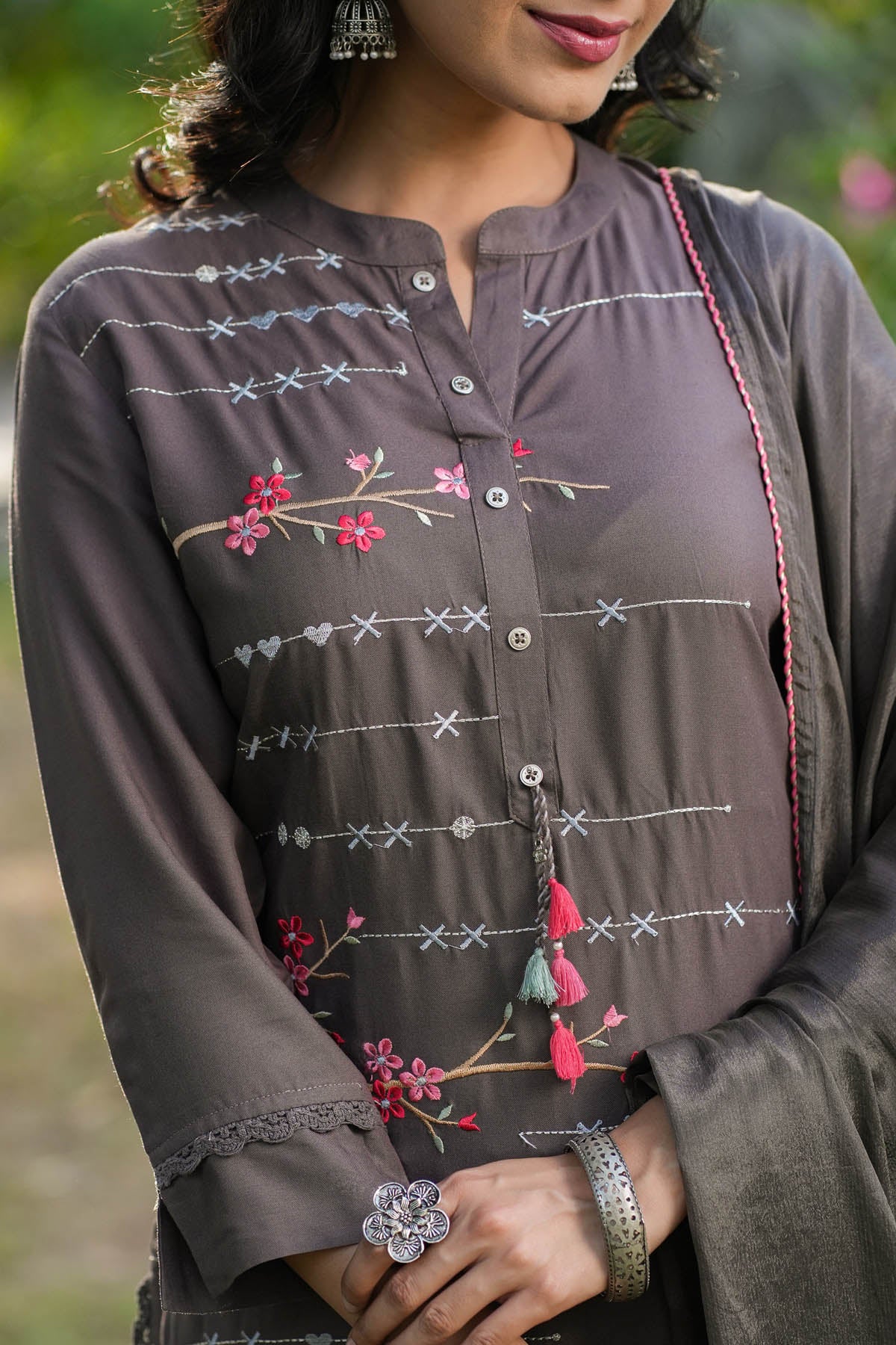 Woman wearing a brown embroidered shirt with floral patterns.