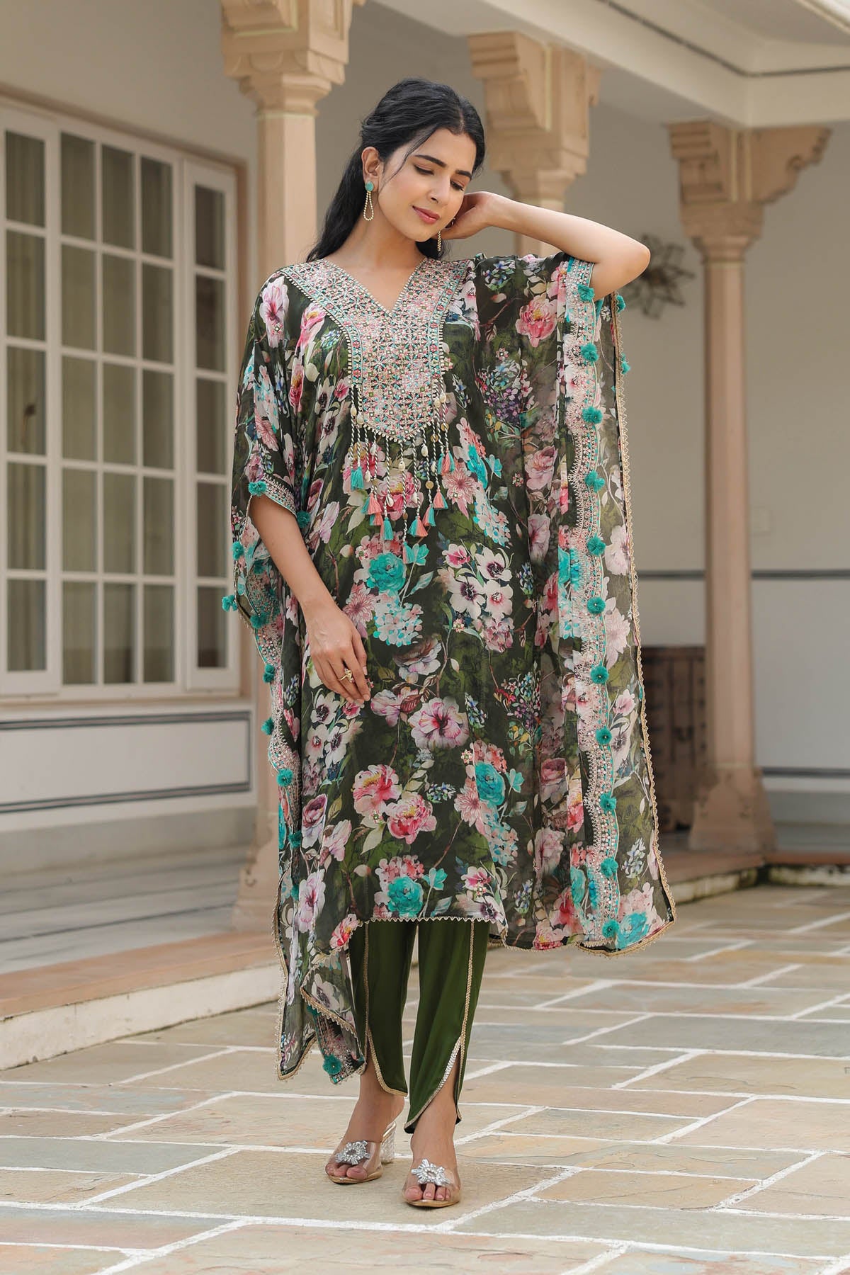 Woman wearing a floral dress and long jacket in an outdoor setting