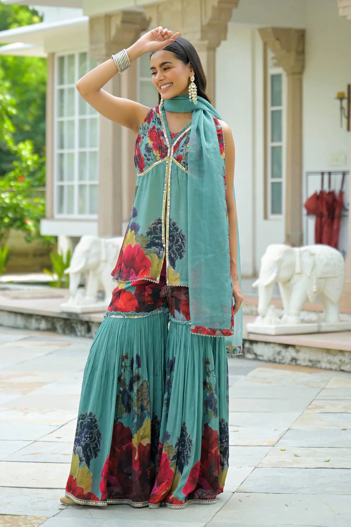 Woman in traditional outfit with floral patterns standing outdoors.