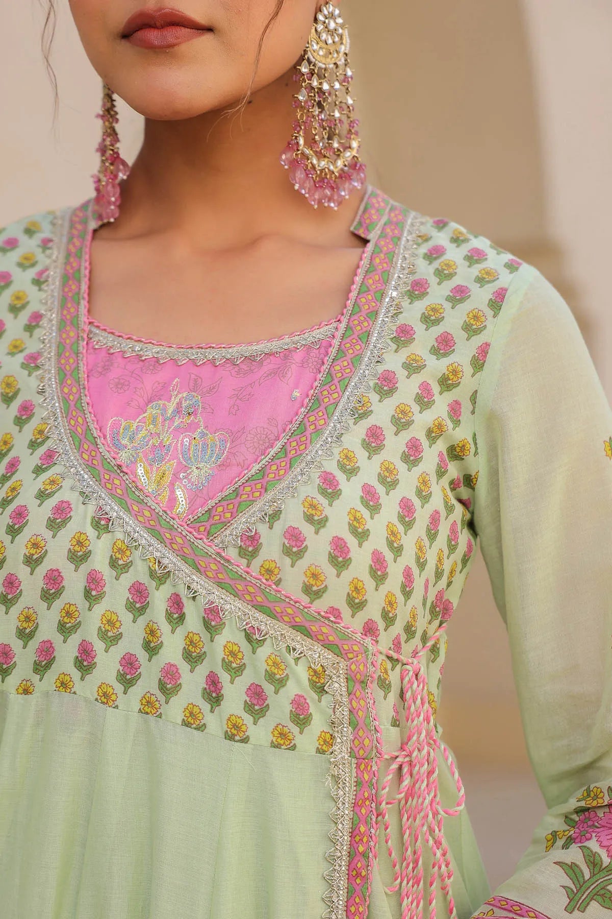 Light green embroidered traditional outfit with pink neckline and floral patterns.