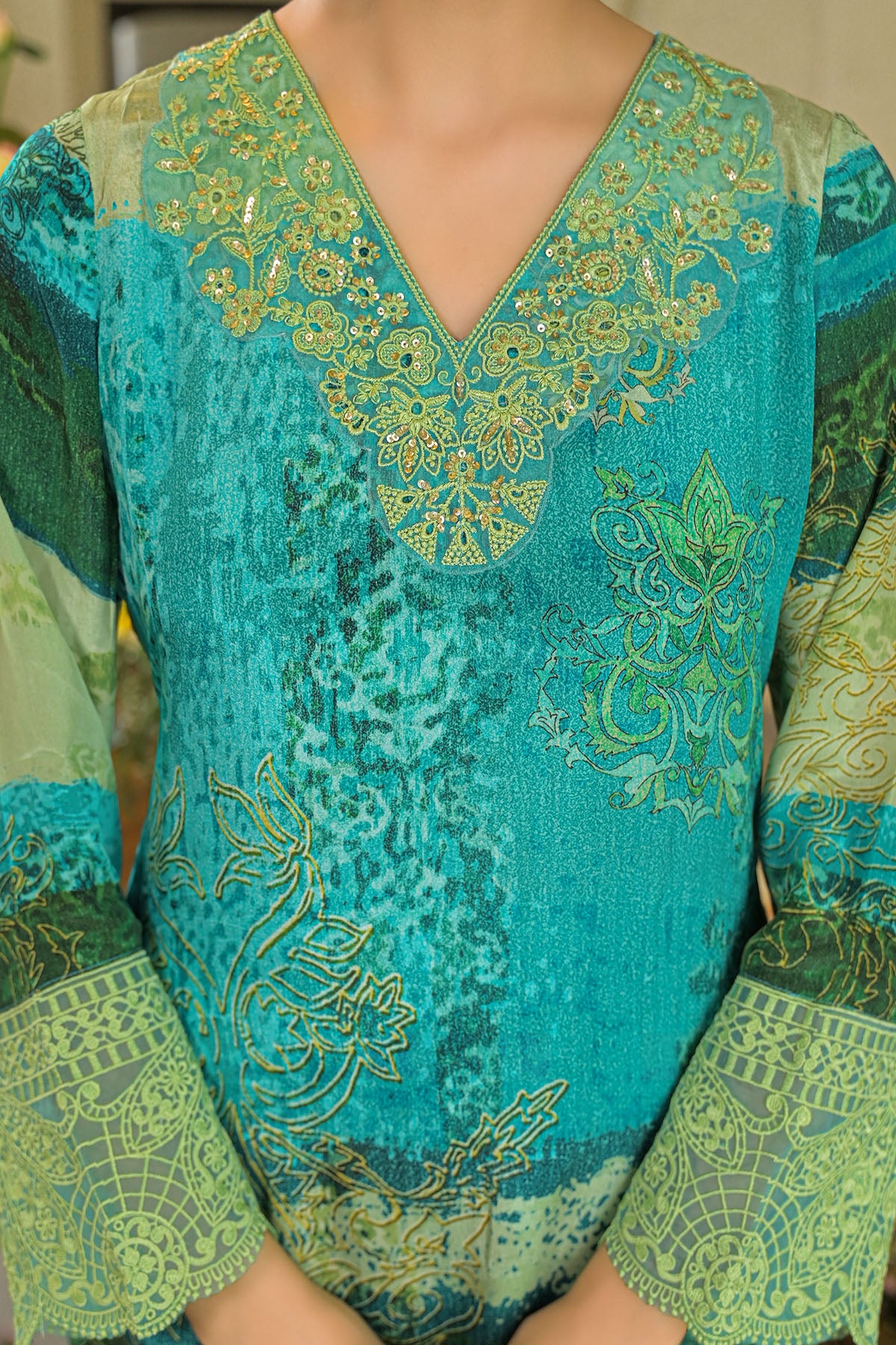Green and blue embroidered traditional outfit with intricate patterns