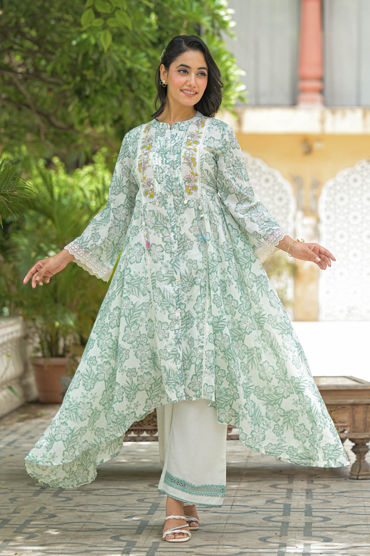 Woman wearing a light green floral kurta with white pants outdoors.
