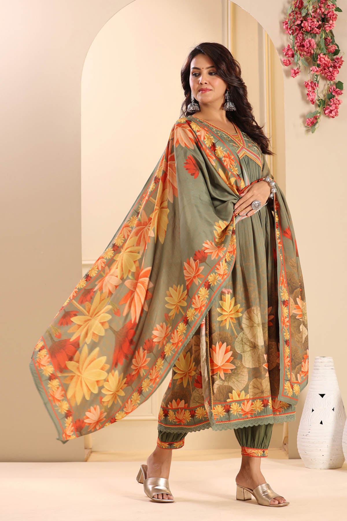 Woman wearing a floral dress with a matching dupatta in an indoor setting.