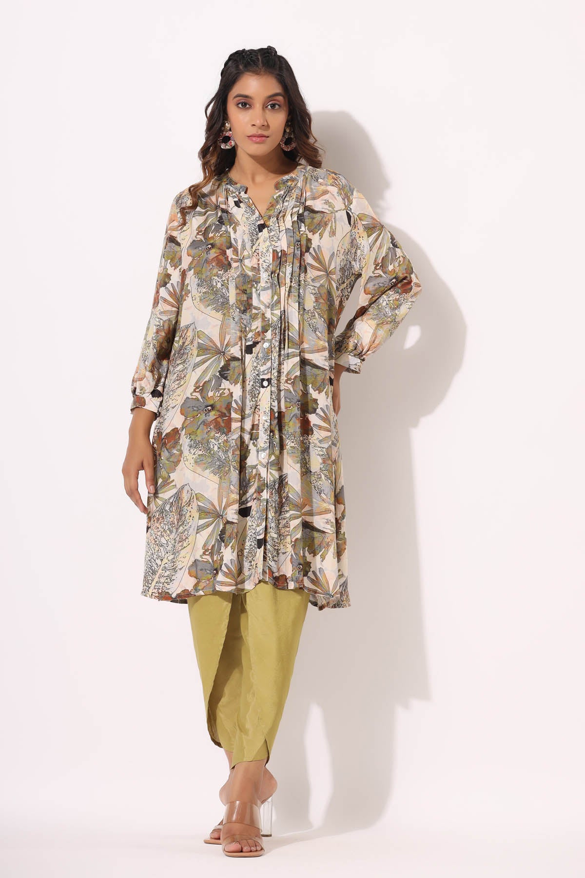 Woman wearing a floral long shirt and green pants on a white background