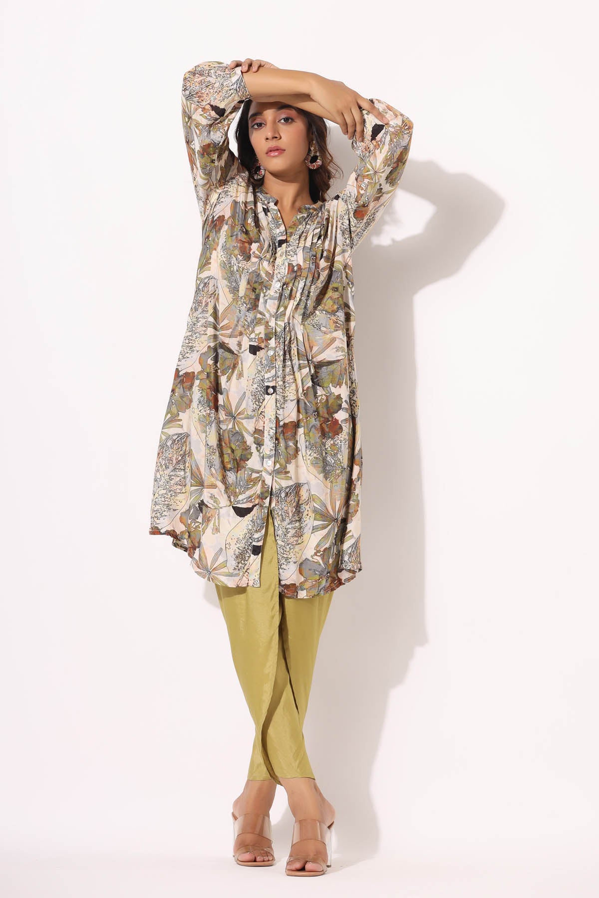 Woman wearing a floral top and yellow pants on a white background