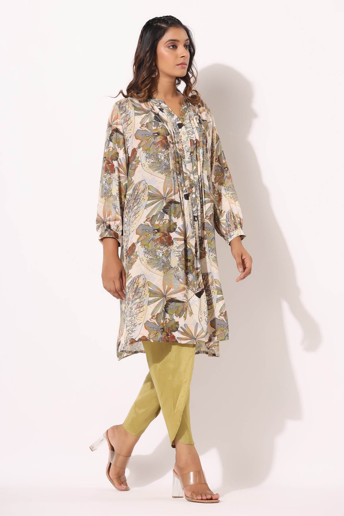 Woman wearing a floral dress and green pants on a white background