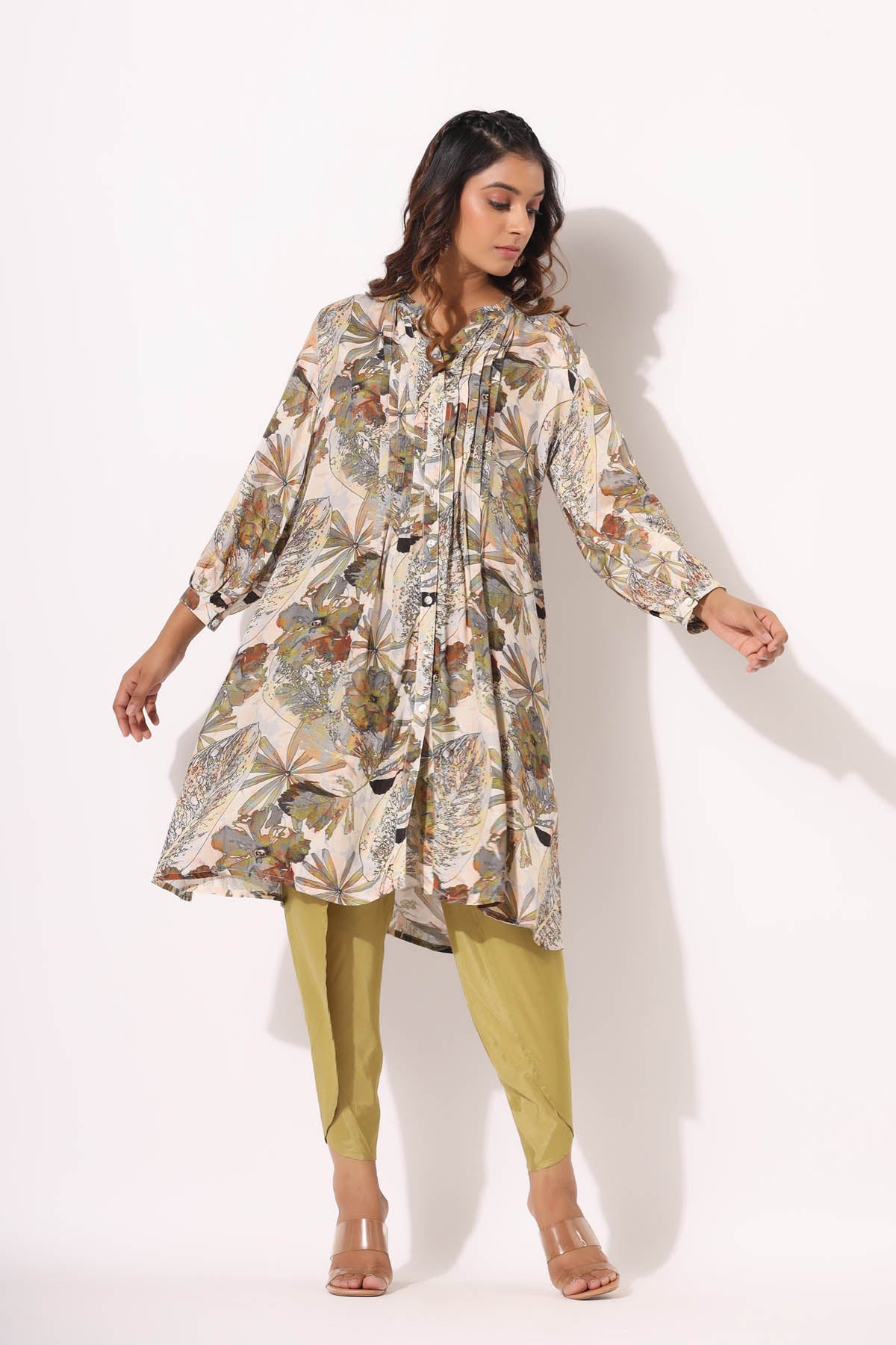 Woman wearing a floral dress and green pants on a white background