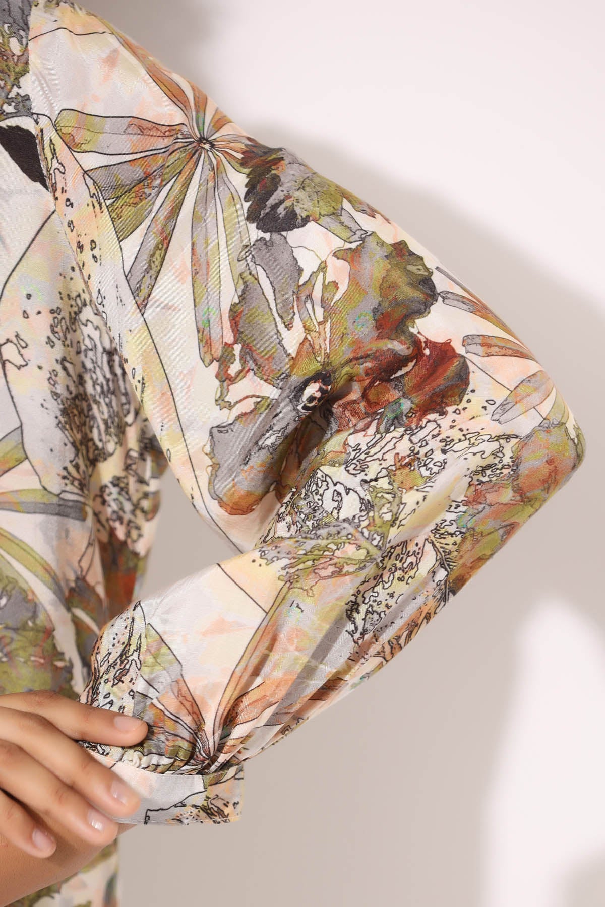 Floral and nature-themed clutch bag held by a hand on a light background