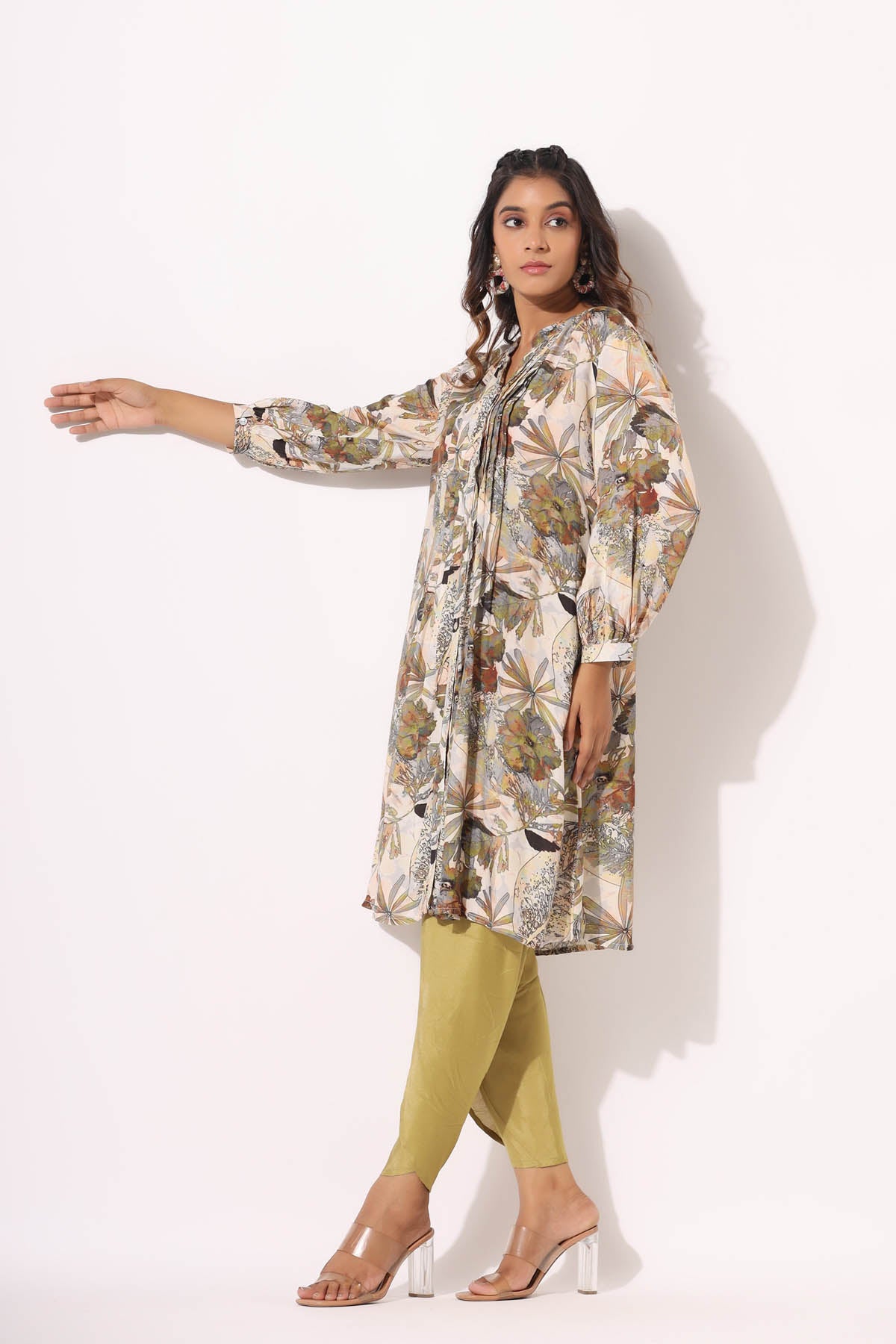 Woman wearing a floral long shirt and green pants on a white background
