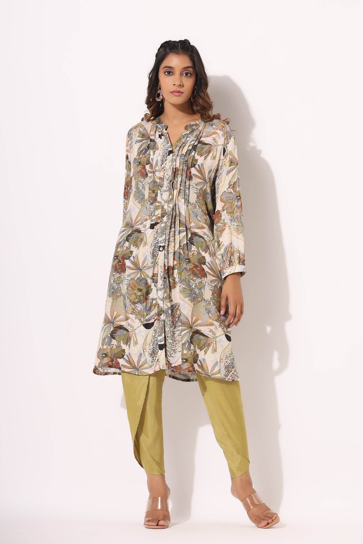 Woman wearing a floral top and green pants on a white background