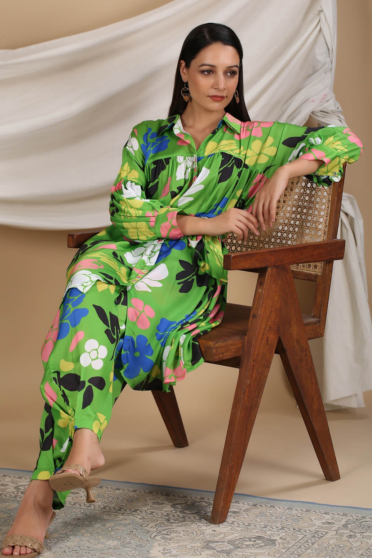 Woman in a colorful outfit sitting on a wooden chair with a neutral background