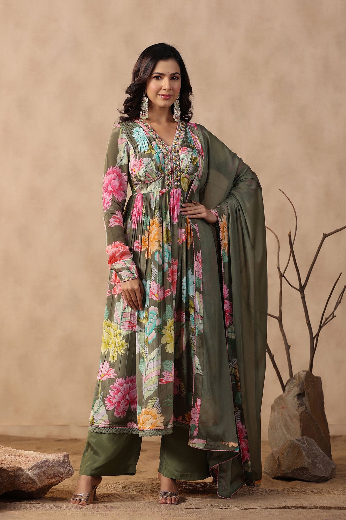 Woman wearing a floral dress with a green dupatta against a beige background