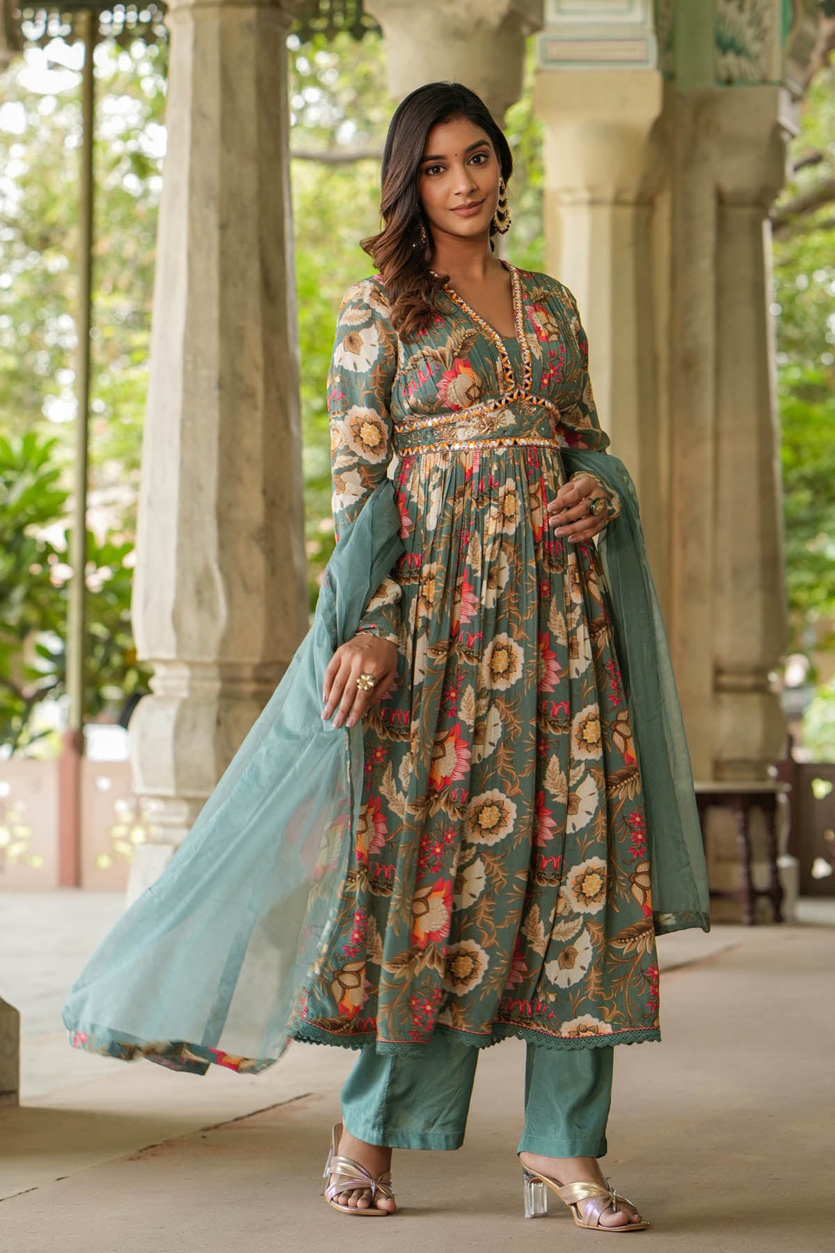 Woman in a floral dress with a green dupatta standing outdoors.