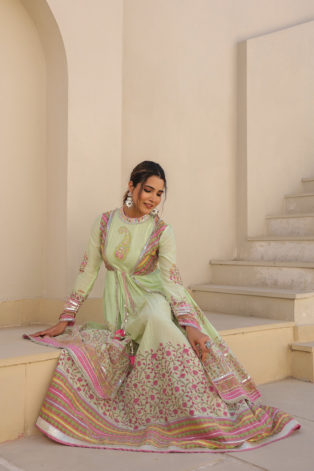 Woman in a traditional outfit sitting on a staircase in an elegant interior setting