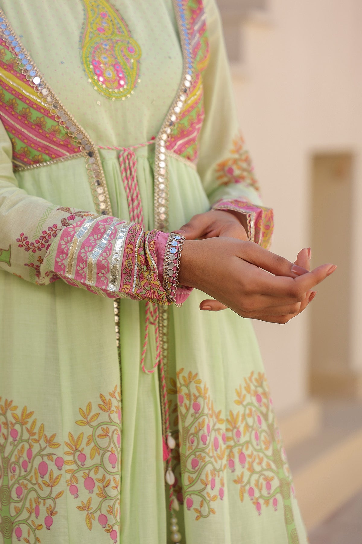 Light green embroidered traditional outfit with pink and gold details.