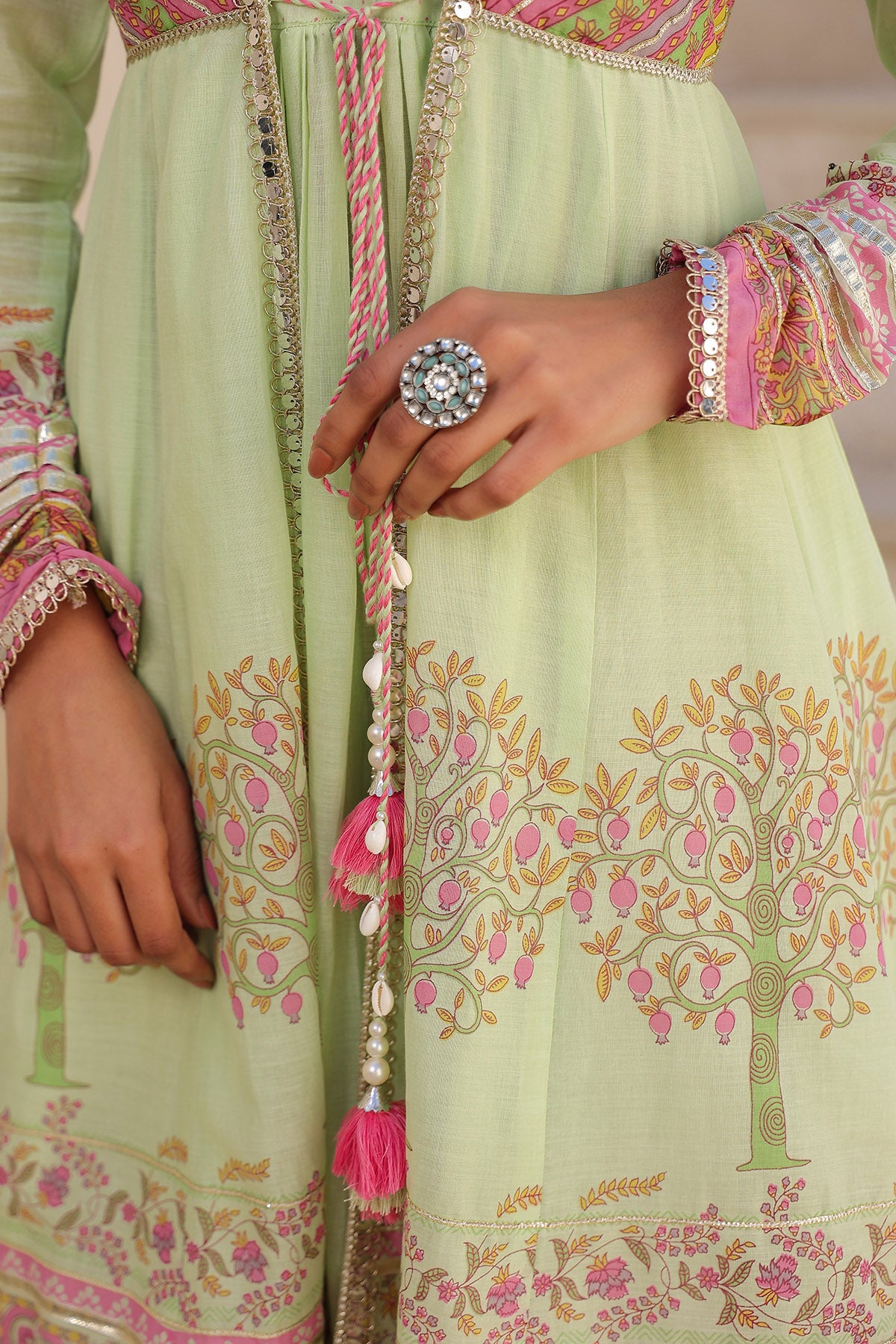 Light green traditional outfit with intricate patterns and a decorative ring.
