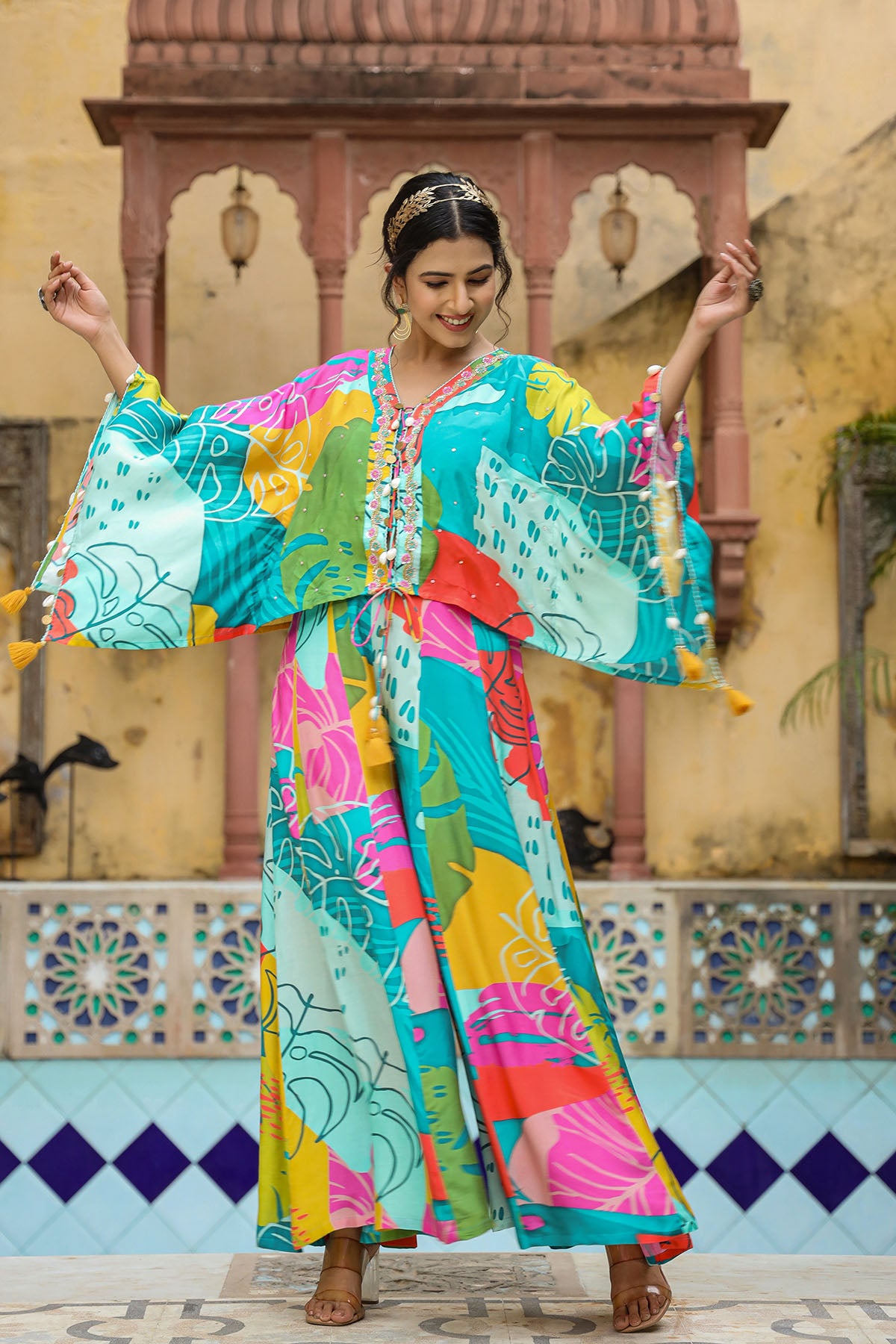 Woman in a colorful traditional outfit dancing in front of a decorative wall.
