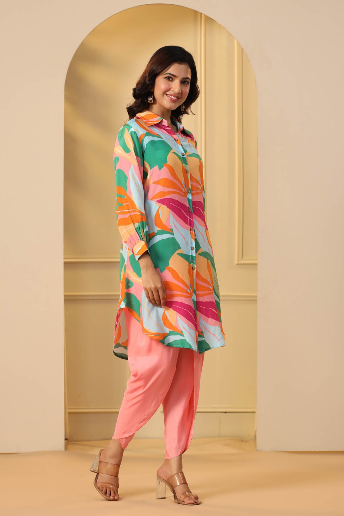 Woman wearing a colorful kurta with pink pants in a minimalistic setting