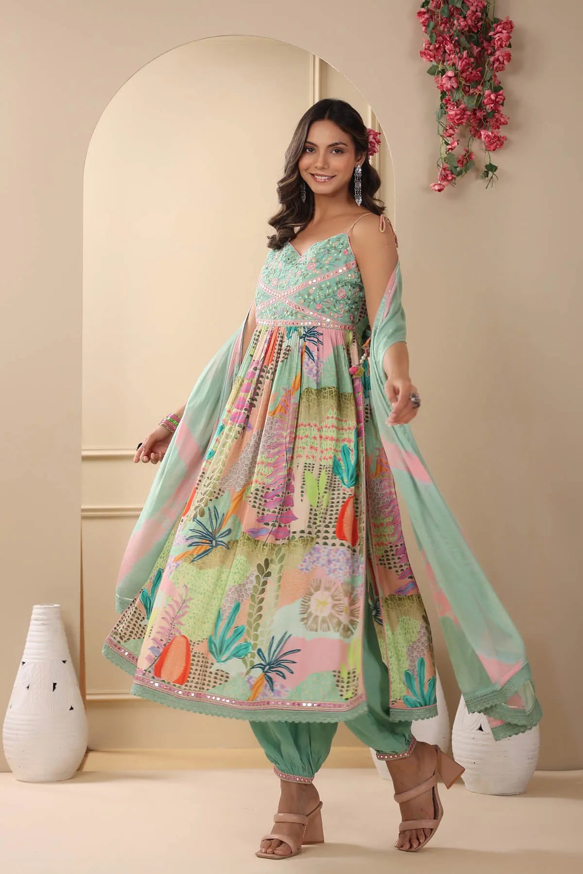 Woman wearing a colorful traditional outfit with floral patterns in a decorated room.