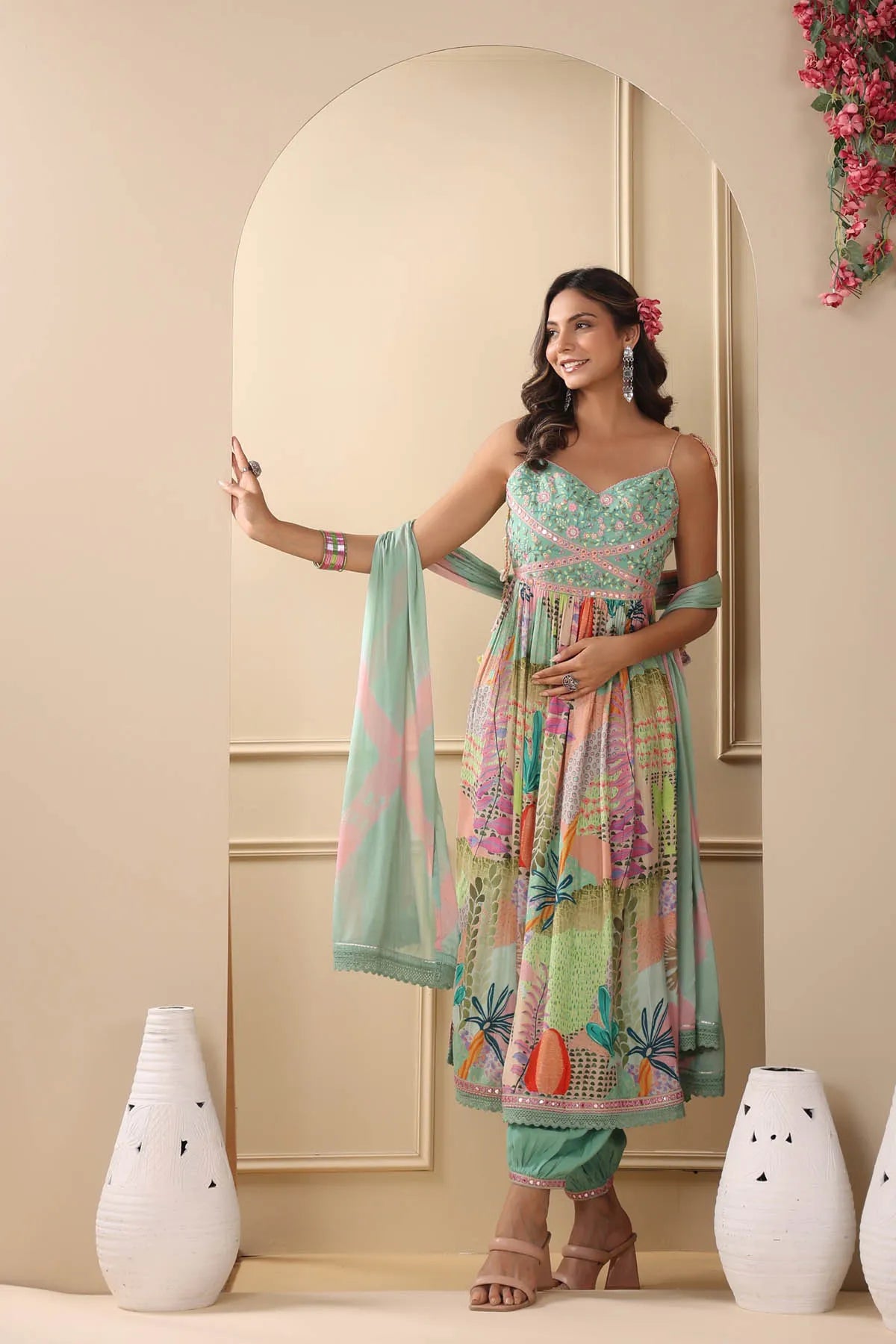 Woman in a colorful traditional outfit standing in a room with decorative elements.