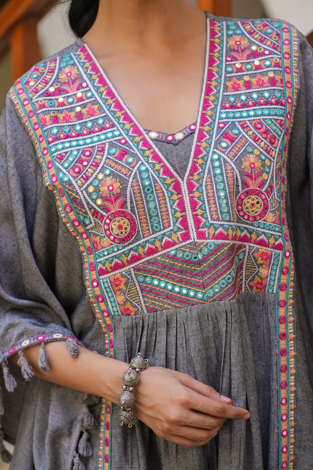 Traditional embroidered garment with vibrant patterns on a gray background