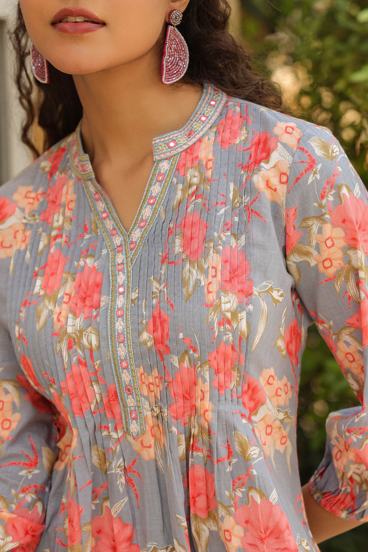 Close-up of a floral dress with pink and red flowers on a blurred natural background