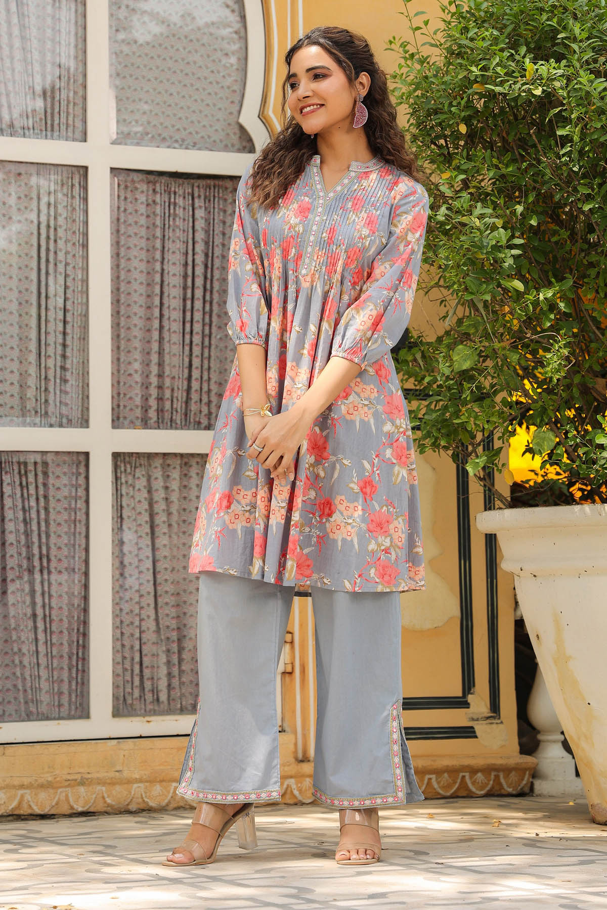 Woman wearing a floral kurta with matching pants standing outdoors.