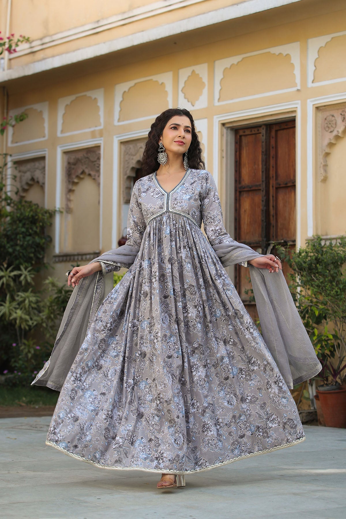 Woman in a floral dress standing in front of an ornate building.