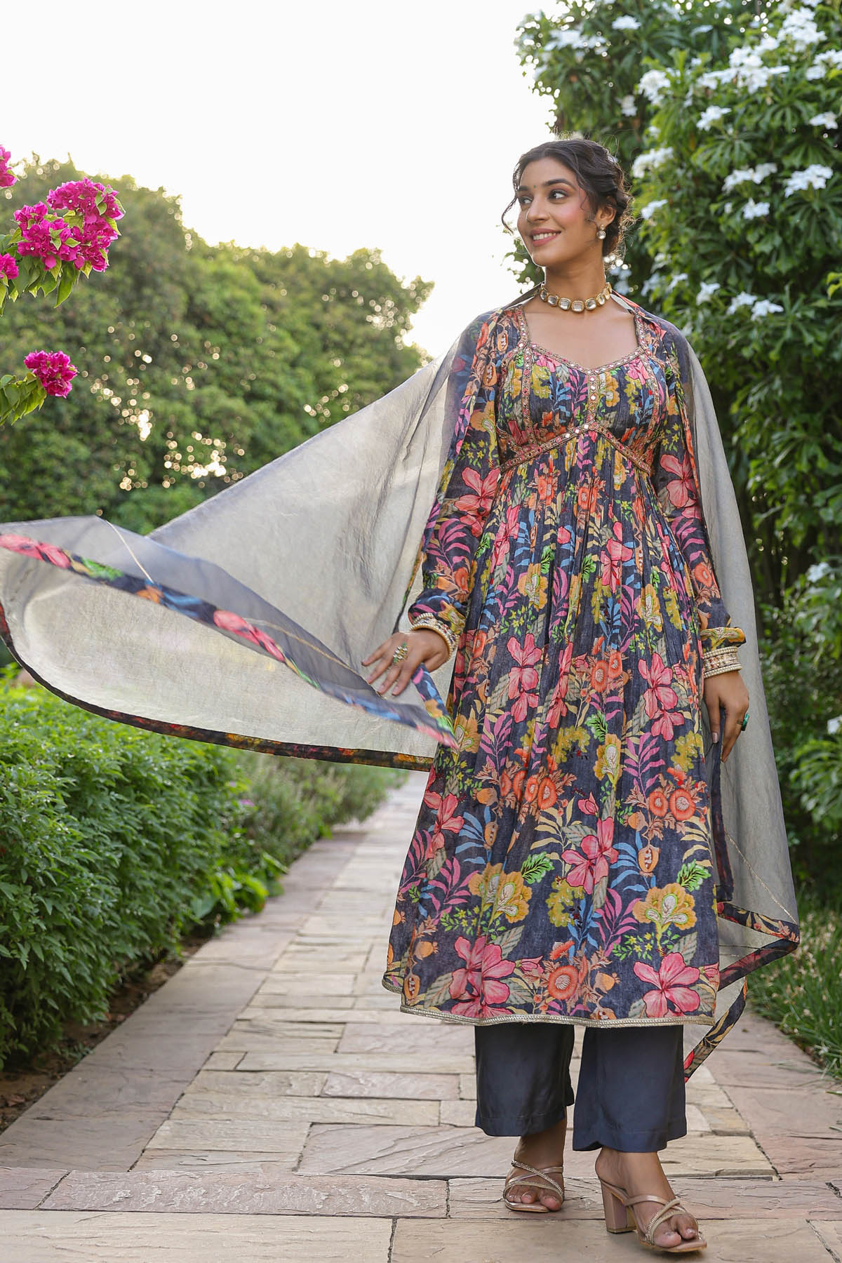 Woman in a floral dress with a dupatta in a garden setting