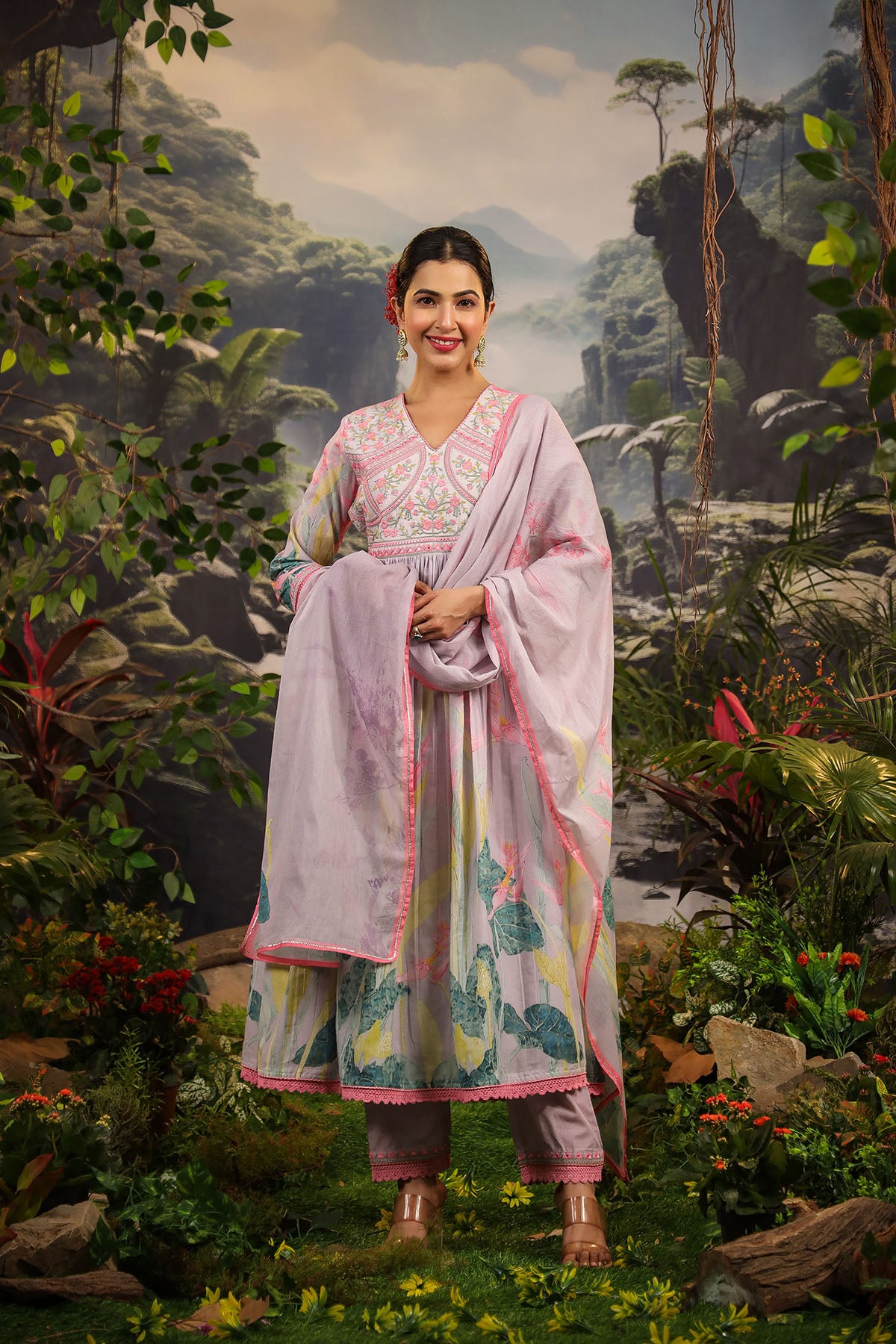 Woman in traditional outfit standing in a lush, painted landscape