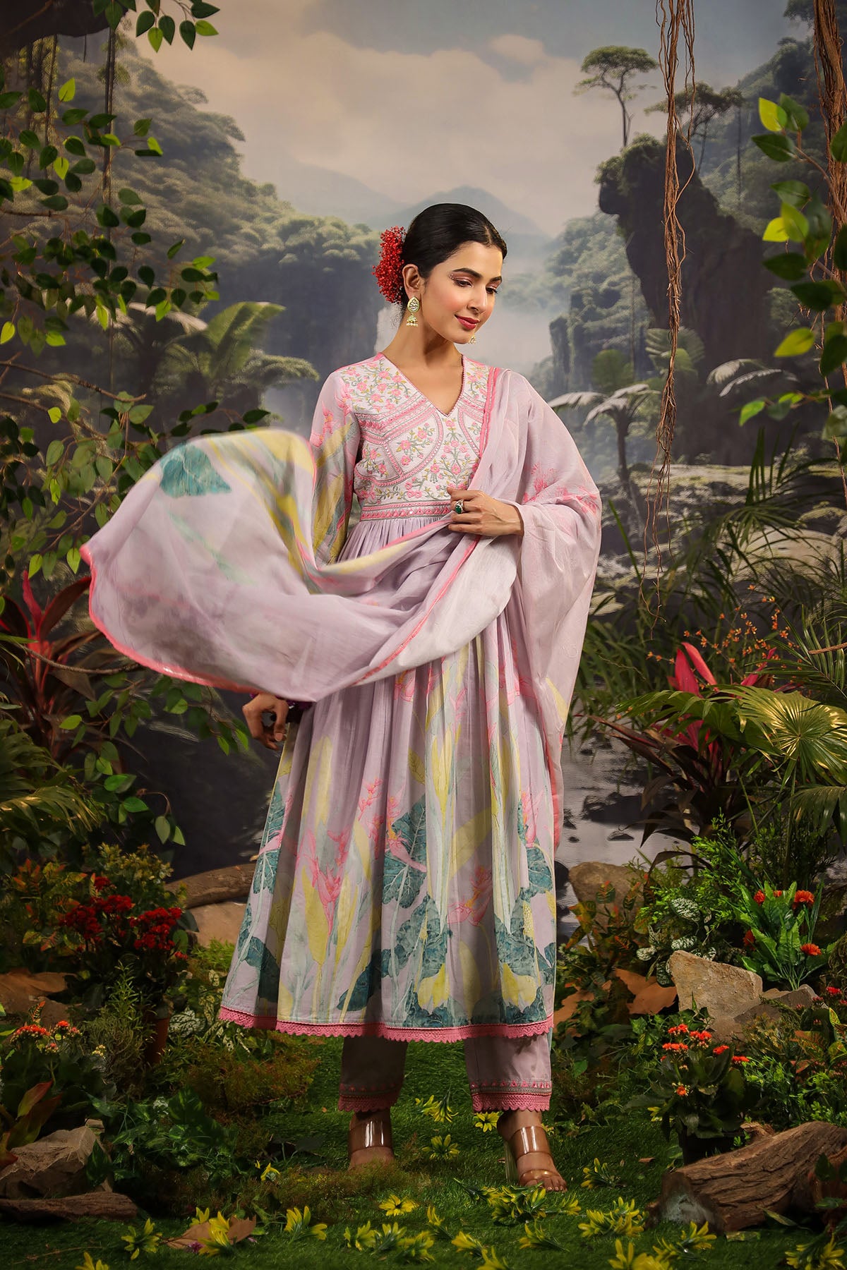 Woman in a traditional outfit standing in a lush, tropical setting