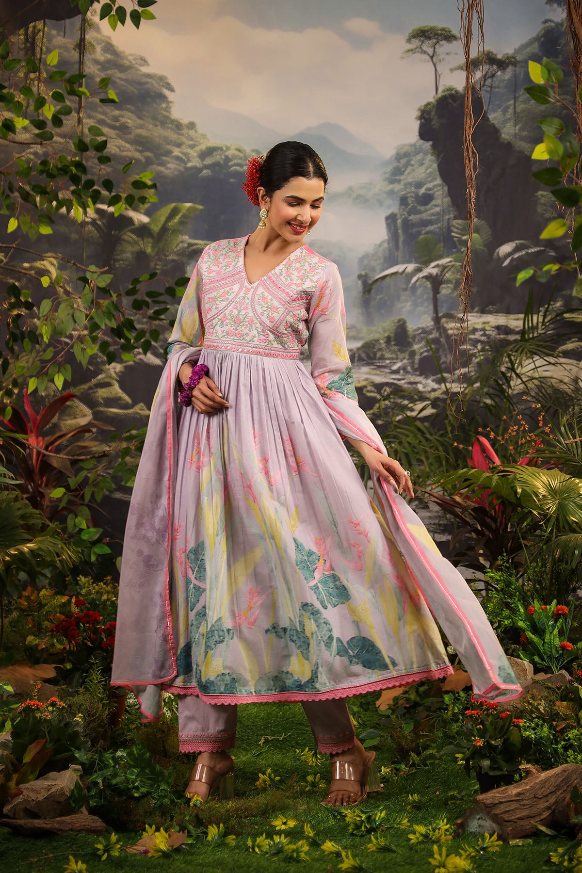 Woman in a floral dress standing in a lush, green forest