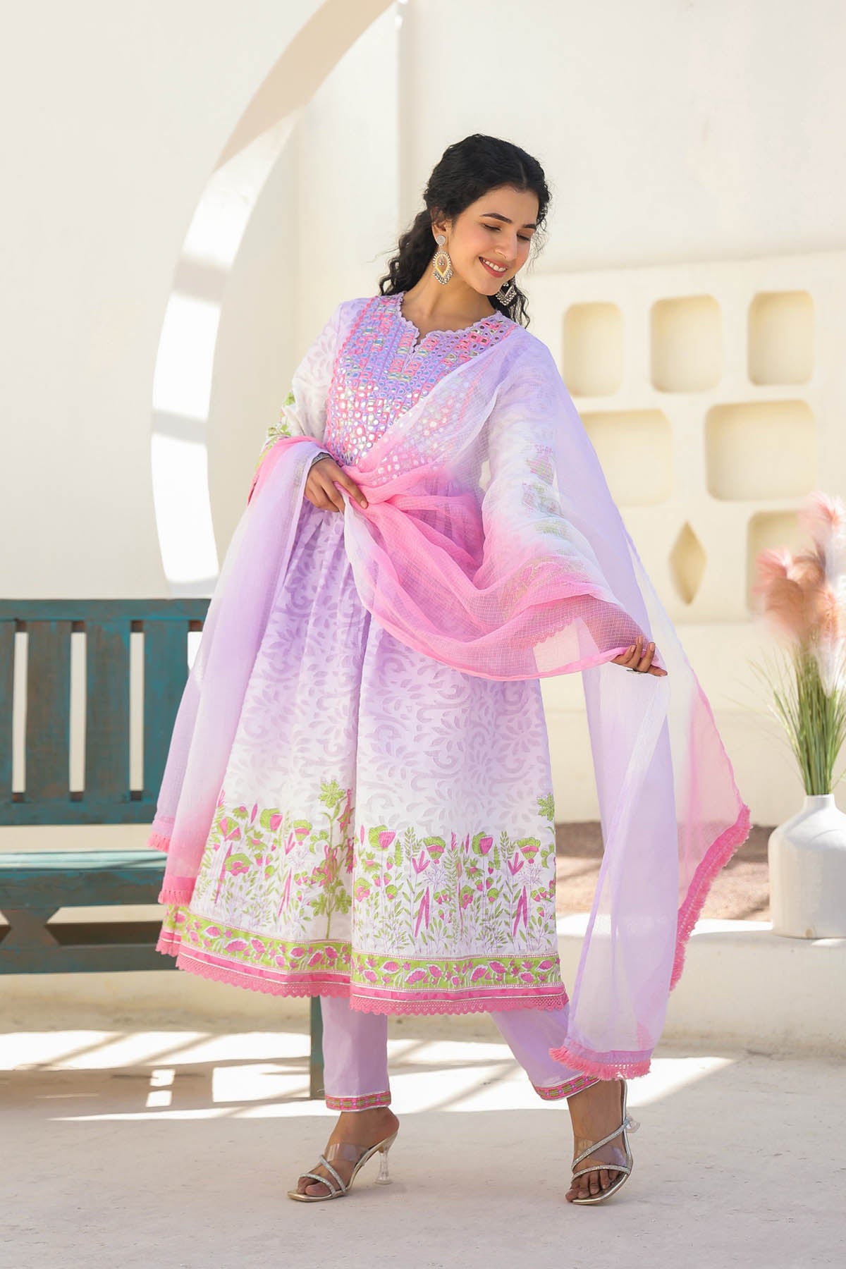 Woman wearing a light purple and pink traditional outfit with floral patterns indoors.