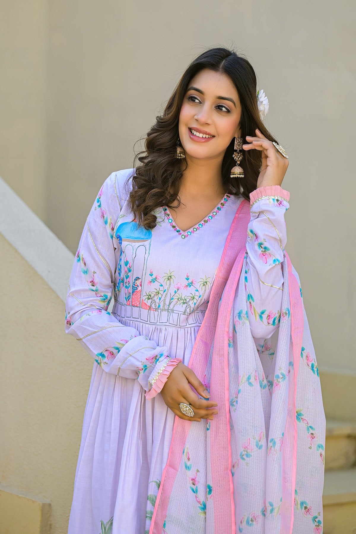 Woman wearing a light purple traditional outfit with floral patterns and a pink dupatta.