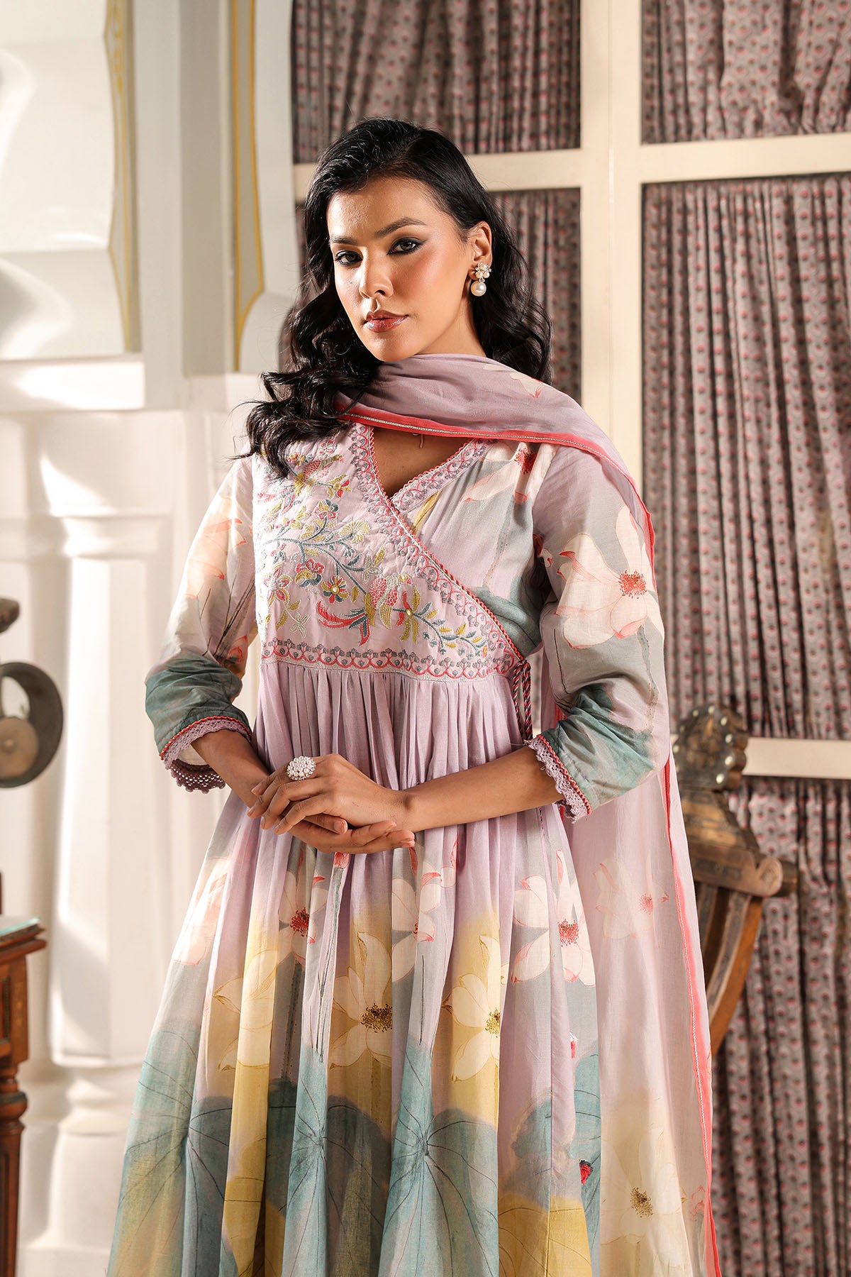 Woman wearing a traditional outfit with floral patterns indoors.