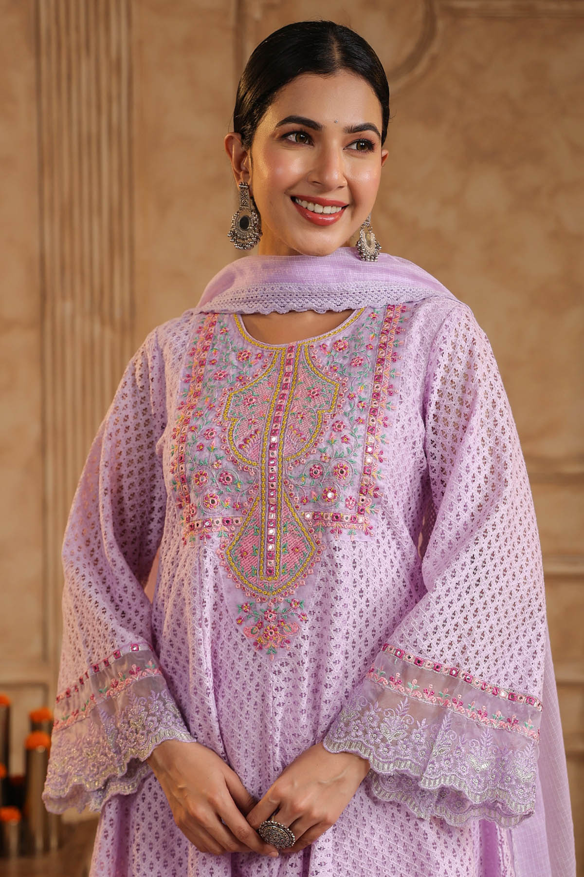 Woman wearing a light purple embroidered traditional outfit with a beige background