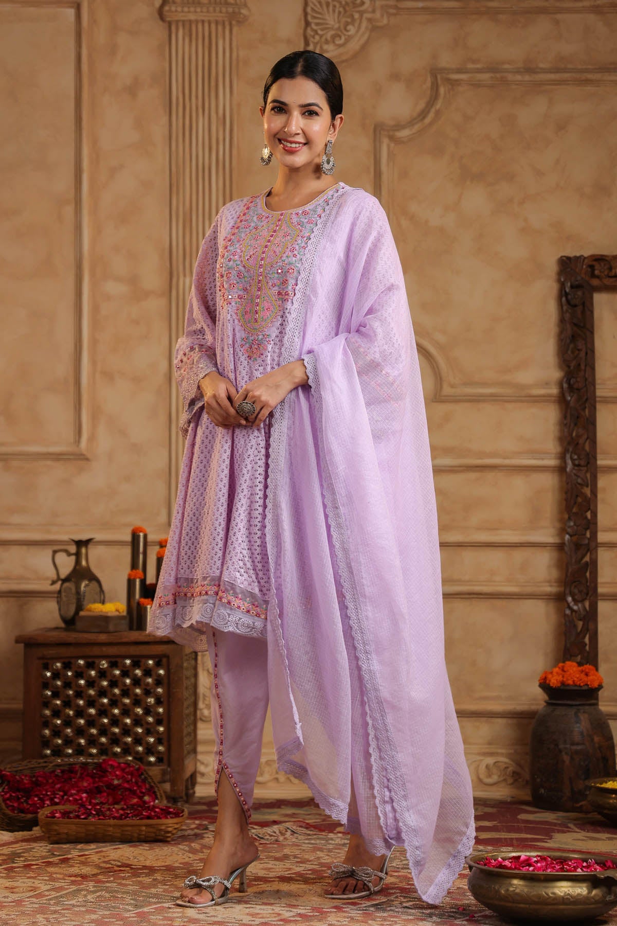 Woman in a light purple traditional outfit standing in an elegant room.