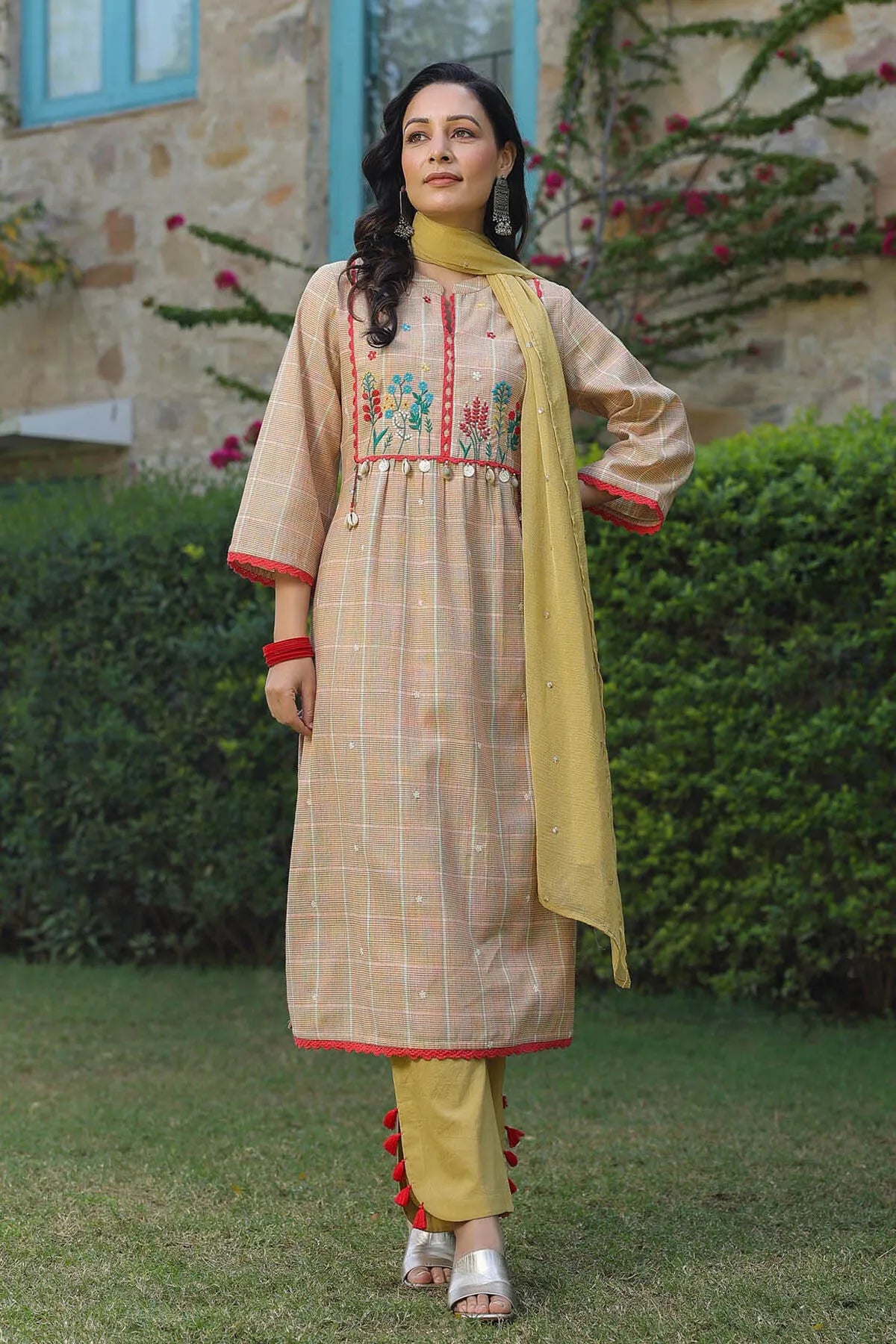 Woman in traditional outfit with floral embroidery standing outdoors.