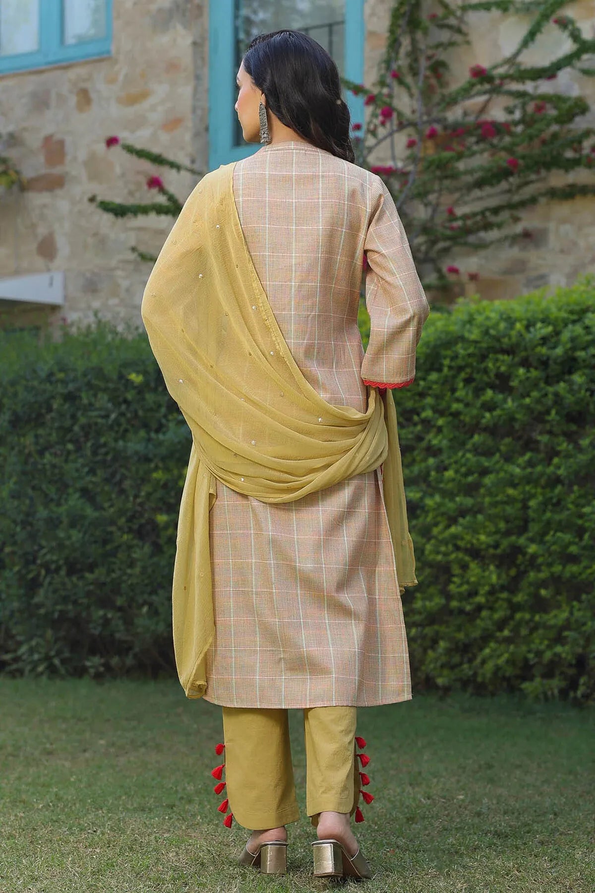 Woman wearing a traditional outfit with a yellow dupatta in an outdoor setting.